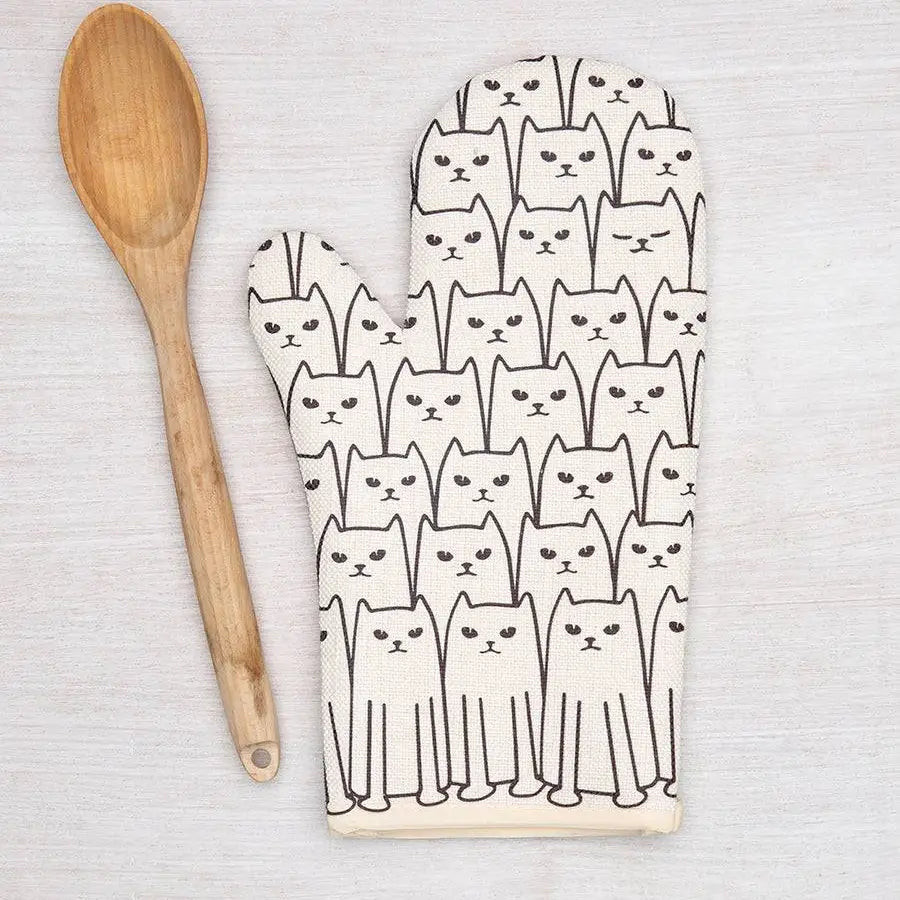 Oven mitt with cat pattern and wooden spoon on a light background