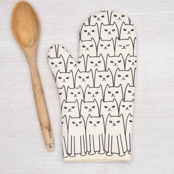 Oven mitt with cat pattern and wooden spoon on a light background