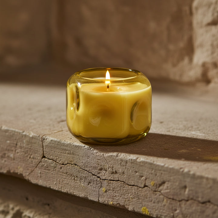 Yellow candle in a glass container on a white background