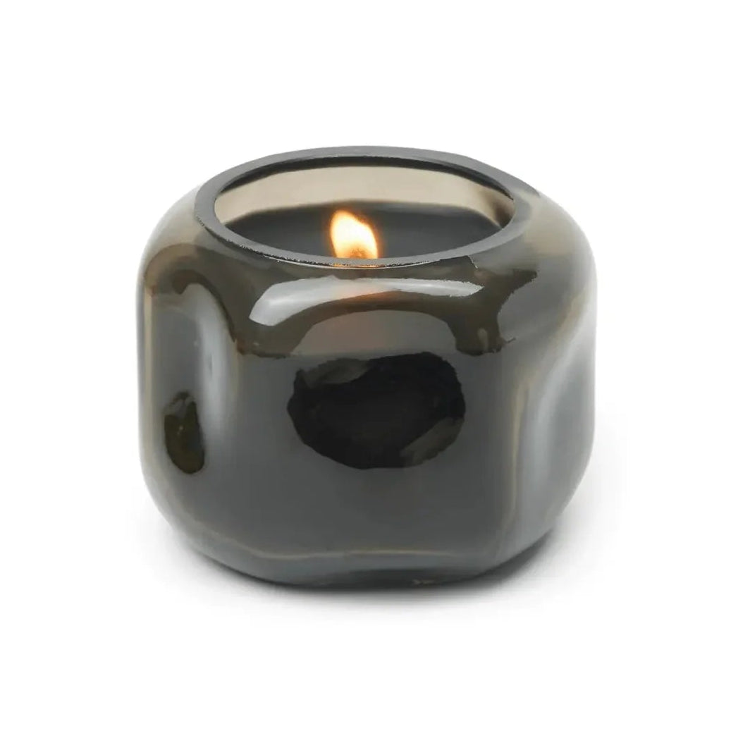 Smoky gray candle holder with a lit candle on a white background