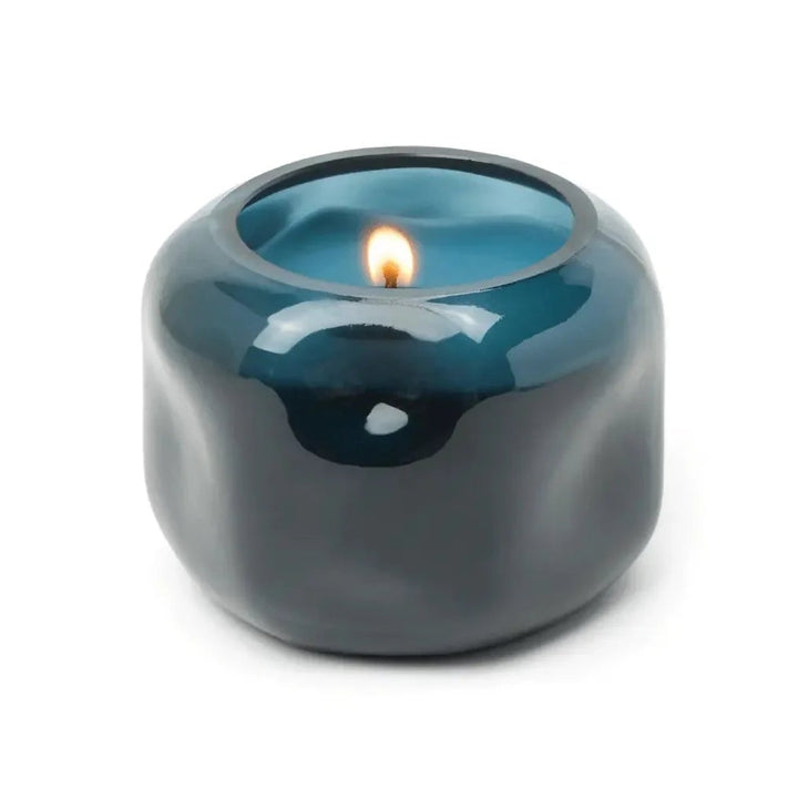 Teal ceramic candle holder with a lit candle on a white background