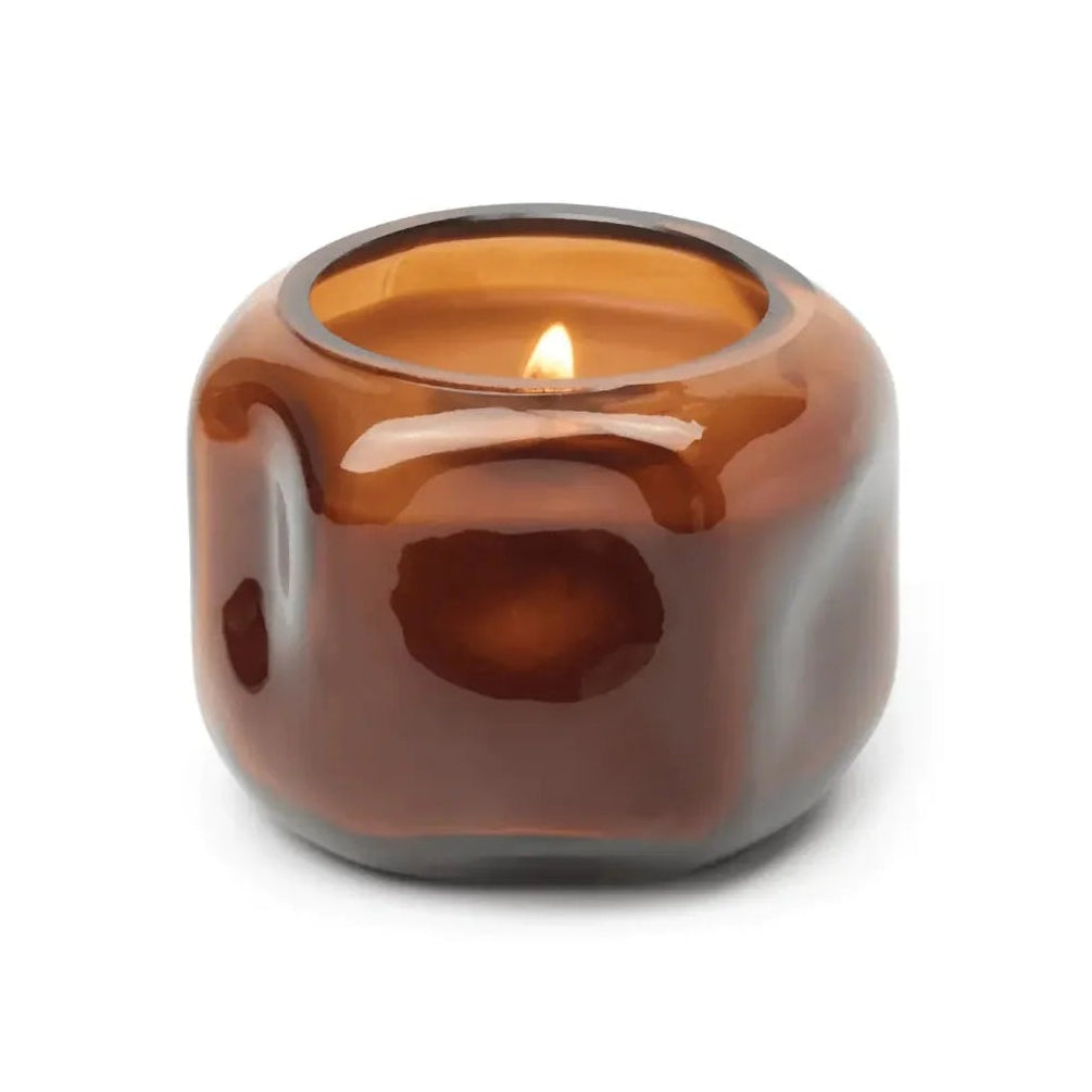 Brown glass candle holder with a lit candle on a white background