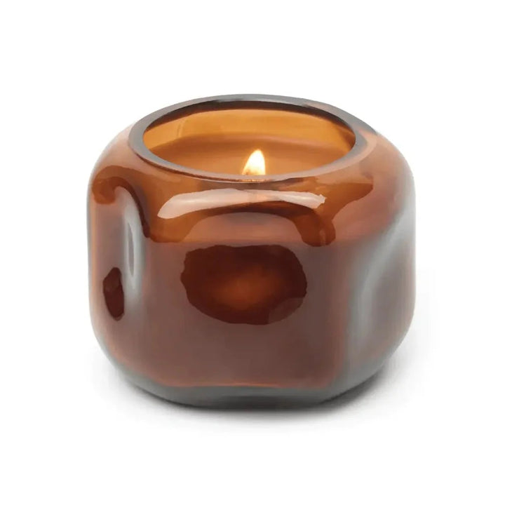 Brown glass candle holder with a lit candle on a white background
